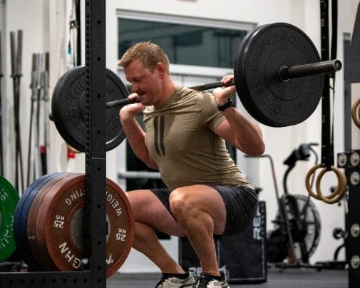 Man doing squats with weights at The Tribe