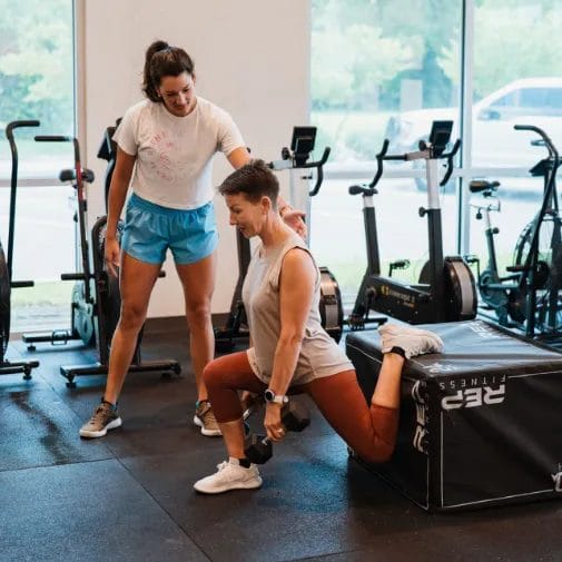 Woman doing squats on pylo box with coach at The Tribe