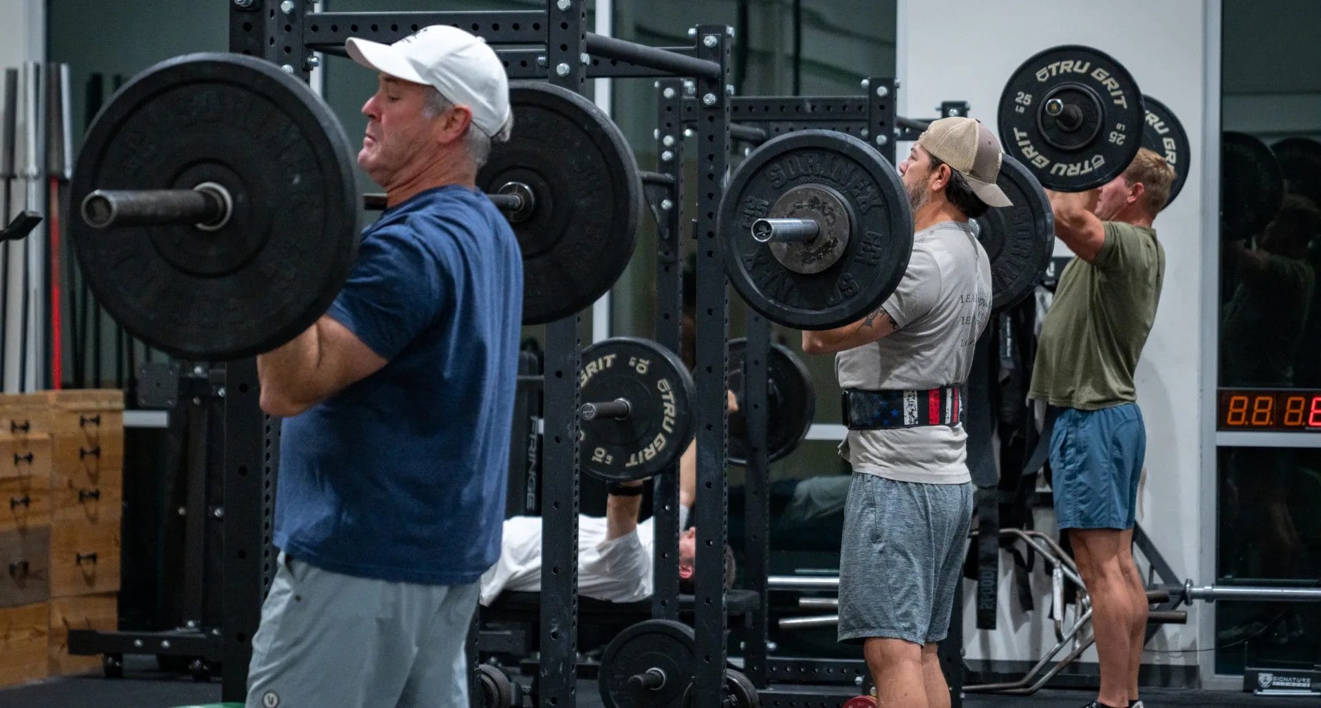 Peoples lift weights at The Tribe